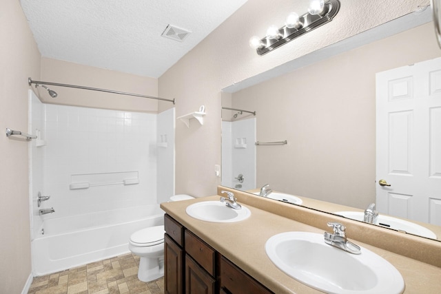 bathroom with toilet, a textured ceiling, visible vents, and a sink