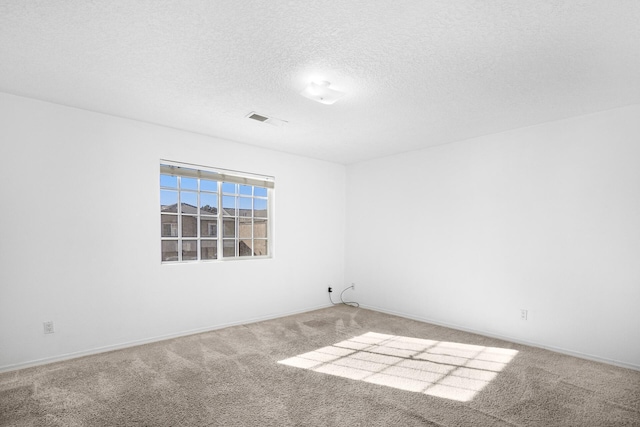 empty room with baseboards, carpet, visible vents, and a textured ceiling