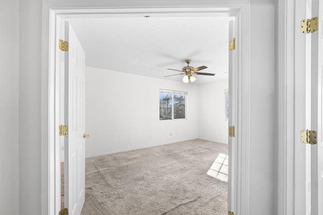 spare room featuring carpet, baseboards, and a ceiling fan