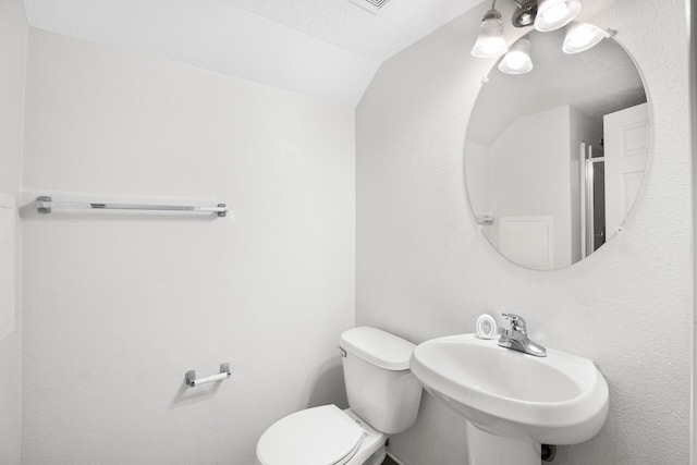 bathroom with vaulted ceiling, a sink, and toilet