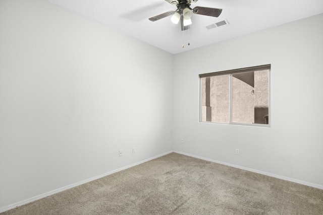 carpeted empty room featuring baseboards, visible vents, and a ceiling fan