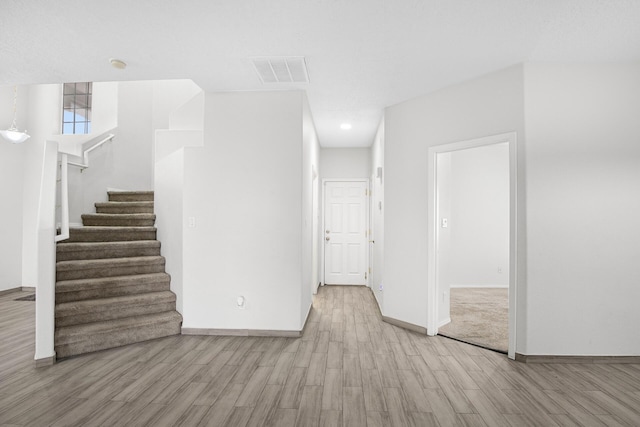 interior space with stairs, visible vents, baseboards, and wood finished floors