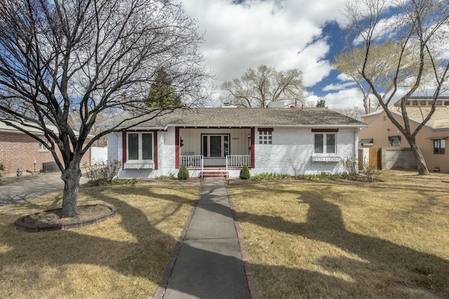 view of front of house featuring a front lawn, a porch, and brick siding