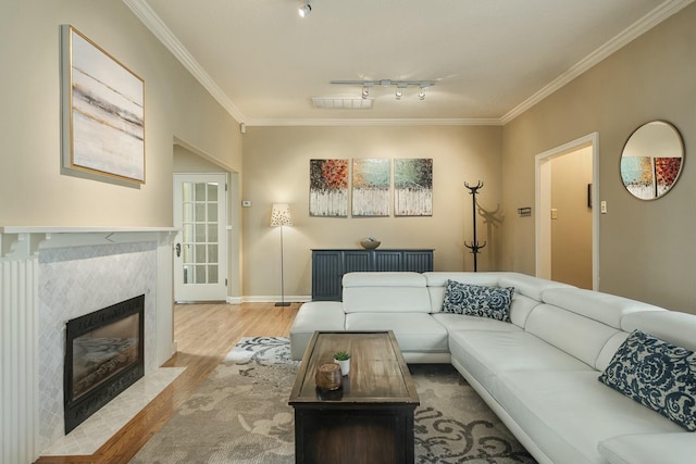 living area featuring a fireplace with flush hearth, baseboards, crown molding, and wood finished floors