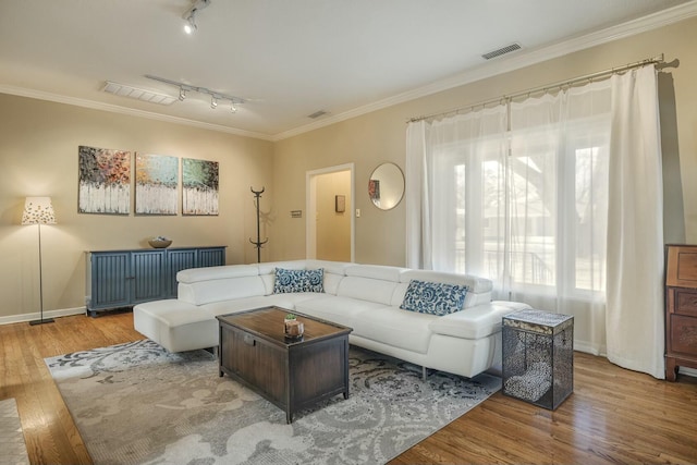 living area with visible vents, crown molding, and wood finished floors