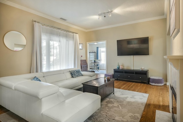 living area featuring visible vents, ornamental molding, and wood finished floors