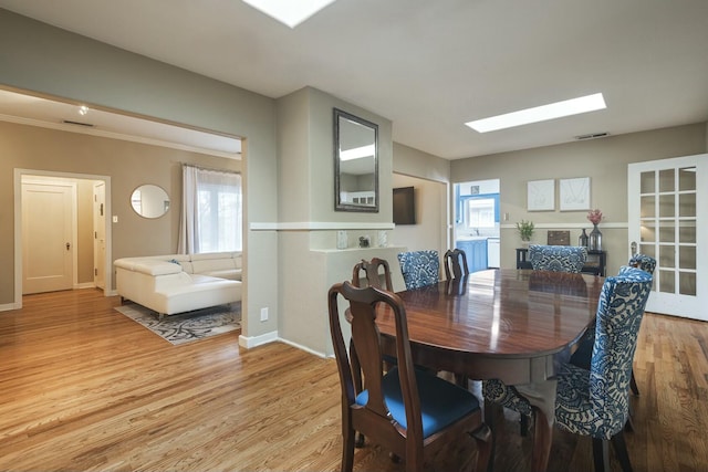 dining space with plenty of natural light, light wood-style flooring, a skylight, and visible vents