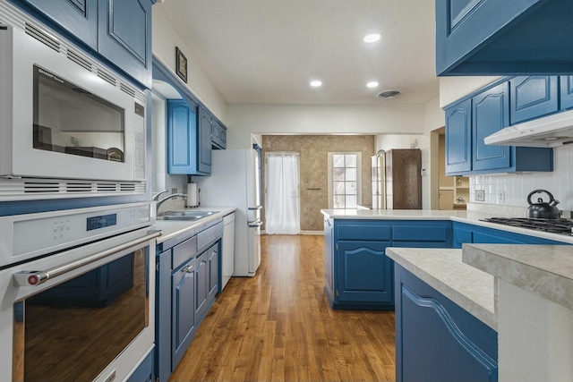 kitchen featuring visible vents, stainless steel microwave, oven, blue cabinets, and a peninsula