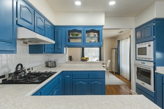 kitchen featuring white appliances, light countertops, and under cabinet range hood