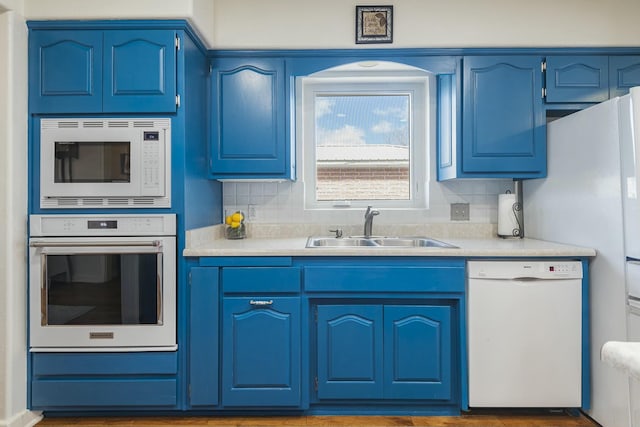 kitchen featuring white appliances, a sink, and blue cabinetry