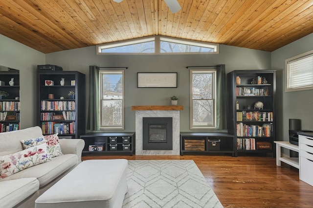 living area featuring a ceiling fan, a glass covered fireplace, lofted ceiling, wooden ceiling, and wood finished floors