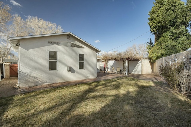 rear view of property featuring a yard, a patio area, a fenced backyard, and stucco siding