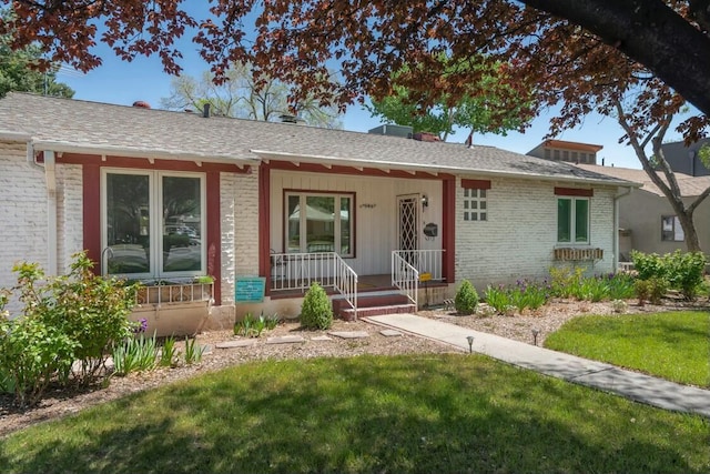 single story home featuring brick siding, a front lawn, and a porch