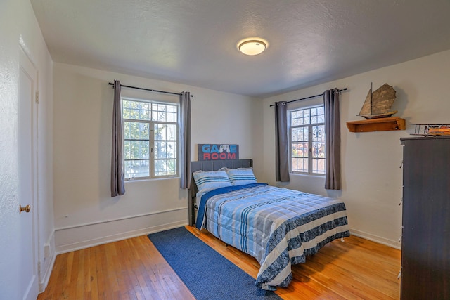 bedroom with hardwood / wood-style floors, multiple windows, and baseboards