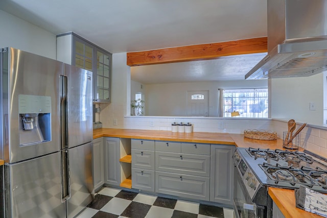 kitchen featuring dark floors, extractor fan, wooden counters, range with gas cooktop, and stainless steel fridge