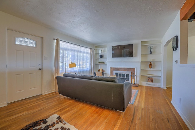 living area featuring light wood-style floors, a fireplace, and a textured ceiling