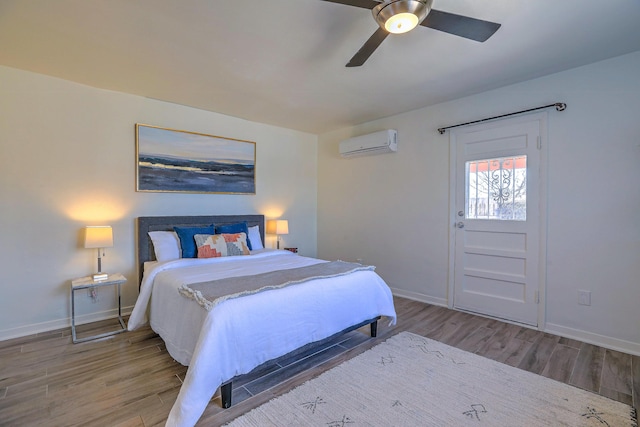 bedroom featuring baseboards, wood finished floors, and a wall mounted AC