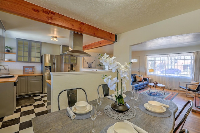 dining room with a textured ceiling, beamed ceiling, and tile patterned floors