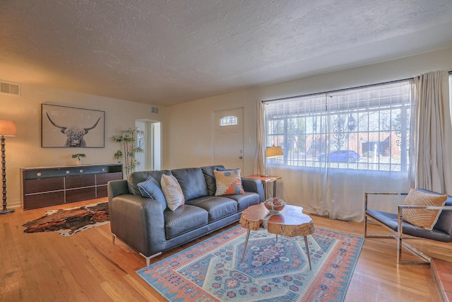 living area featuring a textured ceiling, hardwood / wood-style floors, and visible vents