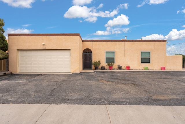 southwest-style home featuring a garage, driveway, fence, and stucco siding