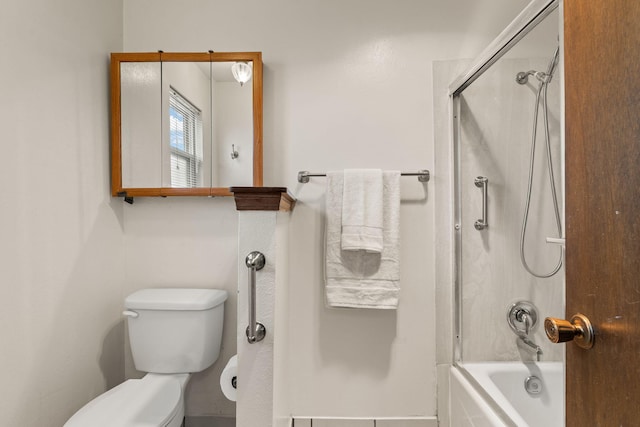 bathroom featuring toilet and bath / shower combo with glass door