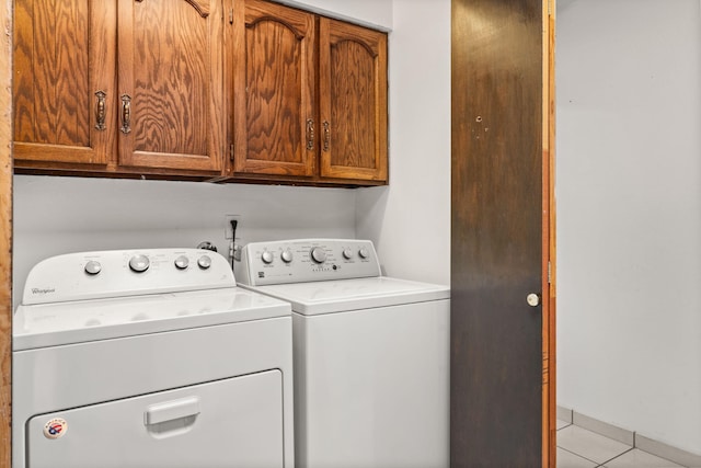 laundry room featuring light tile patterned floors, cabinet space, and separate washer and dryer