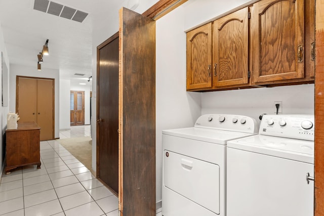 washroom with washing machine and dryer, visible vents, cabinet space, and light tile patterned floors