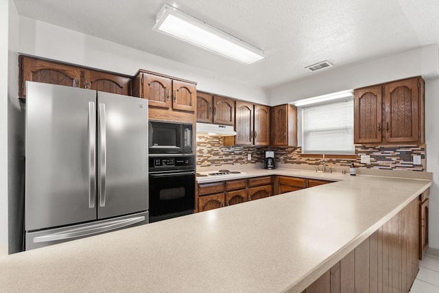 kitchen with black appliances, backsplash, visible vents, and under cabinet range hood