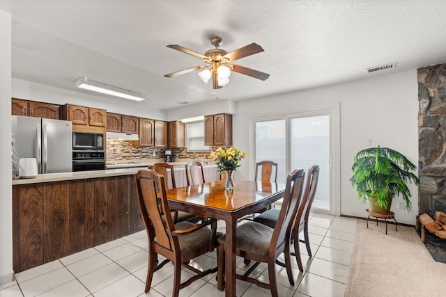 dining room with a ceiling fan, visible vents, a textured ceiling, and light tile patterned flooring