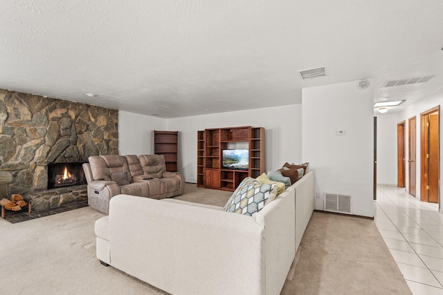 living room with tile patterned flooring, visible vents, a fireplace, and a textured ceiling