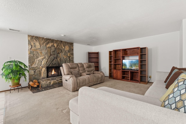 living area with a textured ceiling, a stone fireplace, carpet, and visible vents