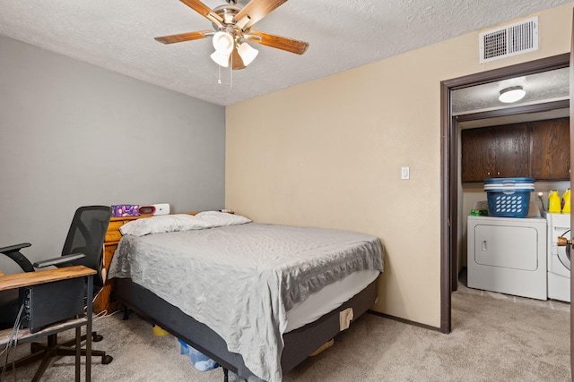 bedroom with carpet floors, visible vents, a ceiling fan, washing machine and dryer, and a textured ceiling