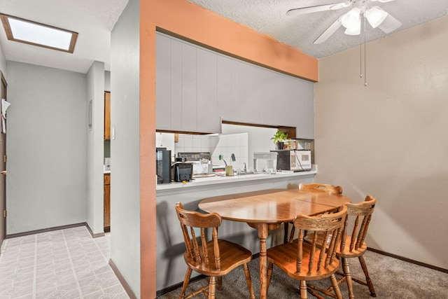 dining space featuring a skylight, a textured ceiling, baseboards, and a ceiling fan