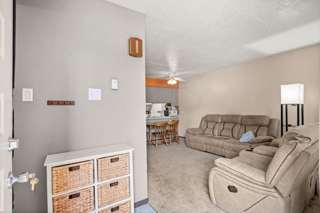 carpeted living room featuring a ceiling fan and a textured ceiling