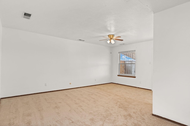 empty room featuring baseboards, visible vents, ceiling fan, carpet, and a textured ceiling