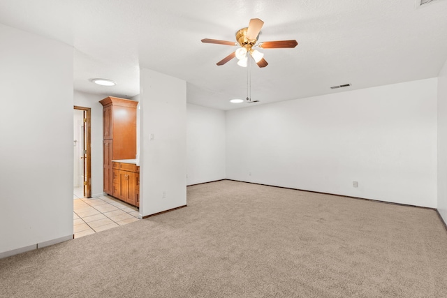 unfurnished room featuring a ceiling fan, light colored carpet, visible vents, and baseboards