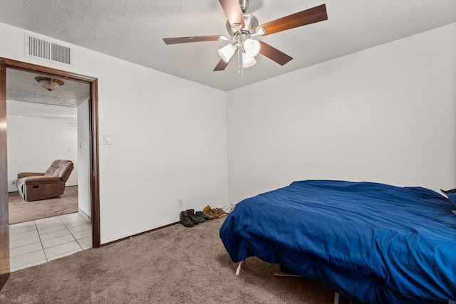 tiled bedroom with visible vents, baseboards, a ceiling fan, carpet, and a textured ceiling