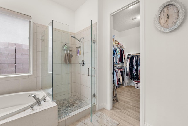 bathroom with a spacious closet, visible vents, a shower stall, a garden tub, and a textured ceiling