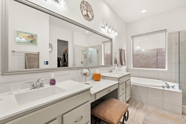 bathroom featuring a garden tub, a spacious closet, a stall shower, and a sink