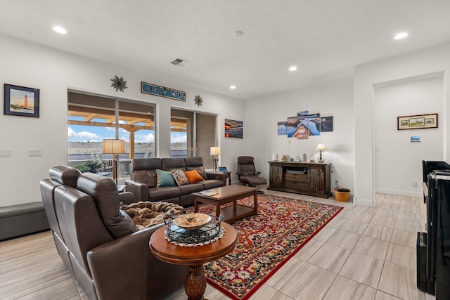 living room with visible vents, recessed lighting, a textured ceiling, and baseboards