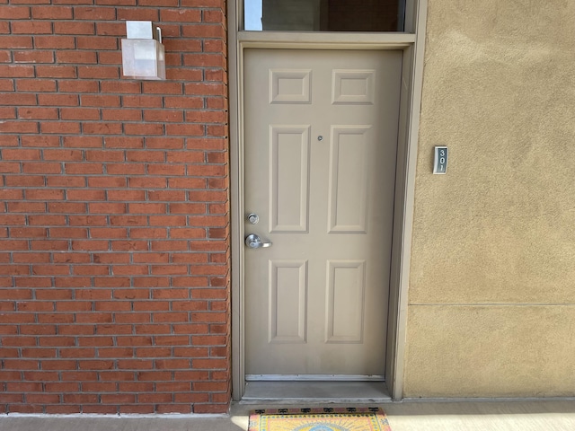 doorway to property with brick siding