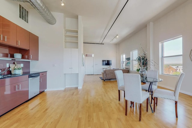 dining area featuring light wood-type flooring, a towering ceiling, visible vents, and track lighting