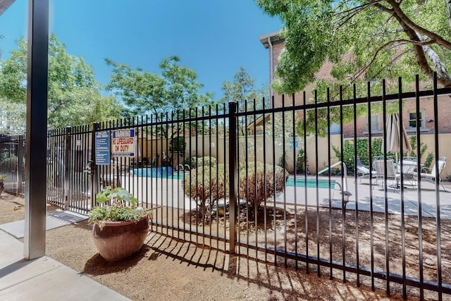 view of gate featuring a pool and fence