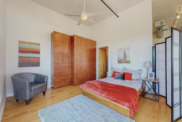 bedroom with a towering ceiling, baseboards, visible vents, and wood finished floors