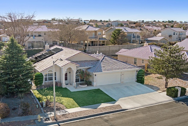 view of front of house featuring a garage, a residential view, concrete driveway, and fence