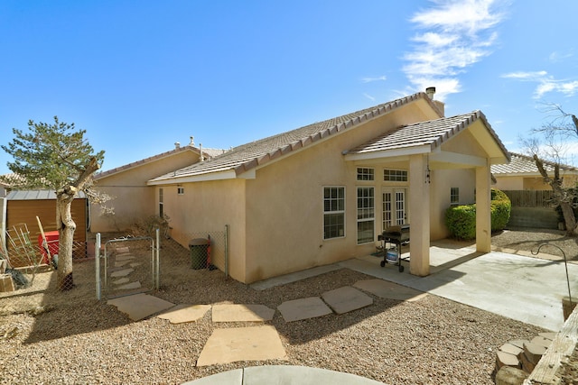 back of property with a patio, stucco siding, a gate, fence, and a tiled roof