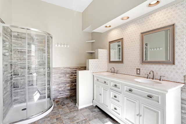 bathroom with double vanity, a sink, tile walls, and a shower stall