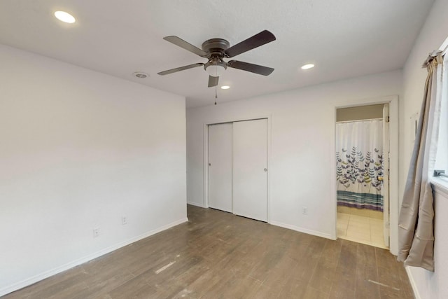 unfurnished bedroom featuring a closet, recessed lighting, baseboards, and wood finished floors