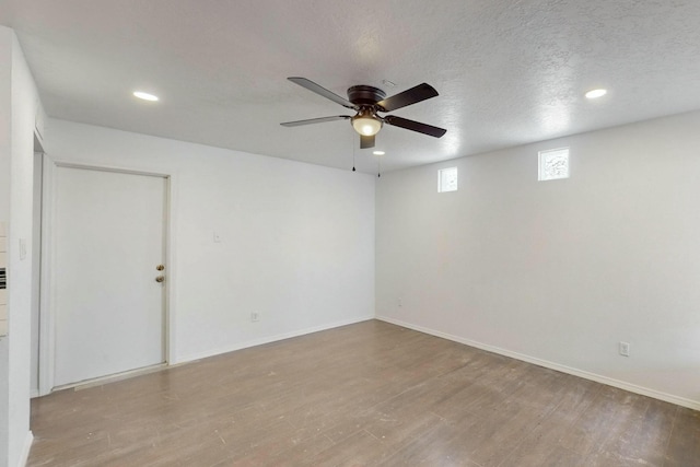 empty room with a textured ceiling, wood finished floors, recessed lighting, baseboards, and ceiling fan