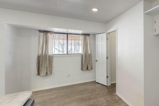 interior space featuring recessed lighting, baseboards, and wood finished floors